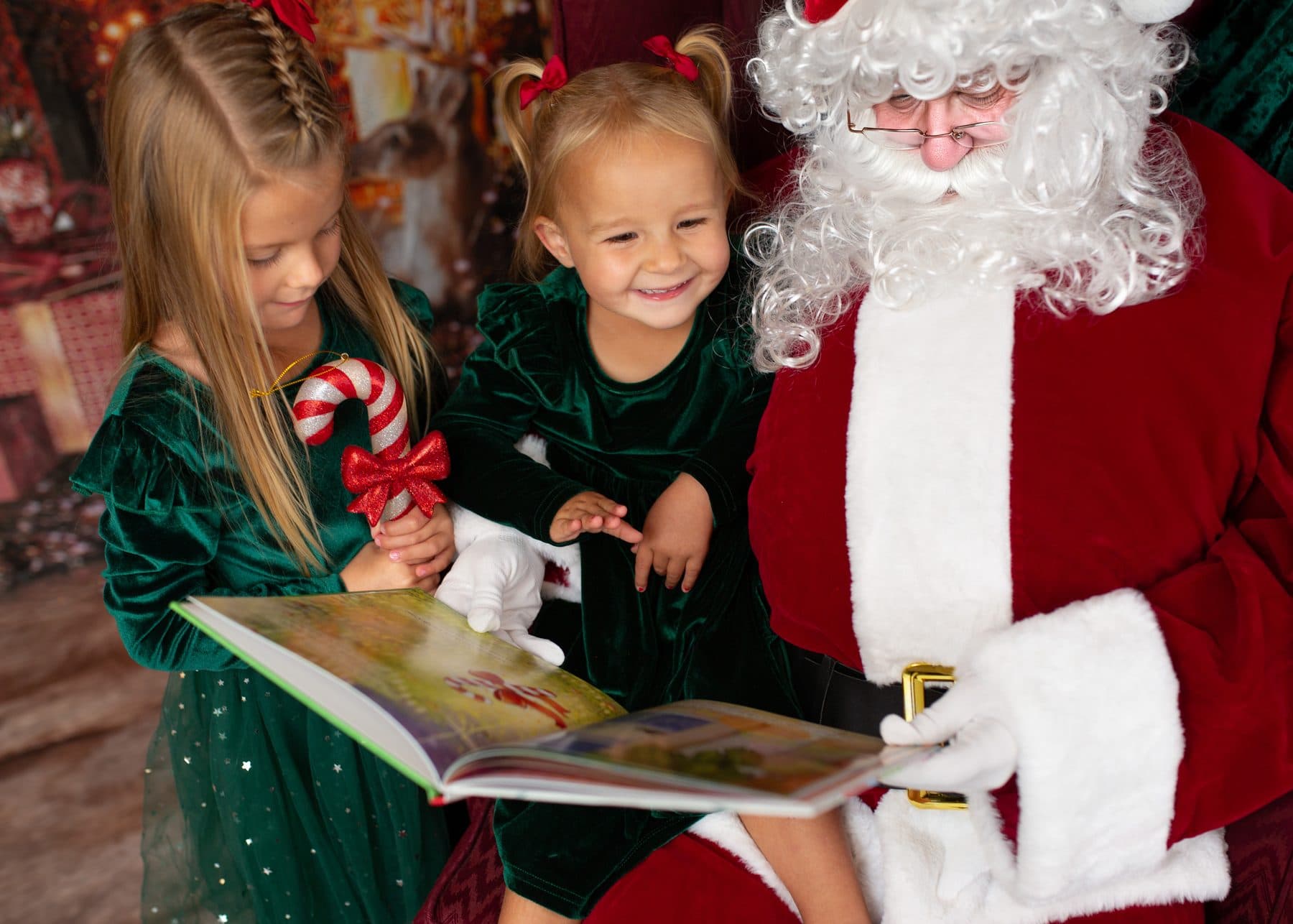 Two sisters reading The Magic Candy Cane storybook with Santa
